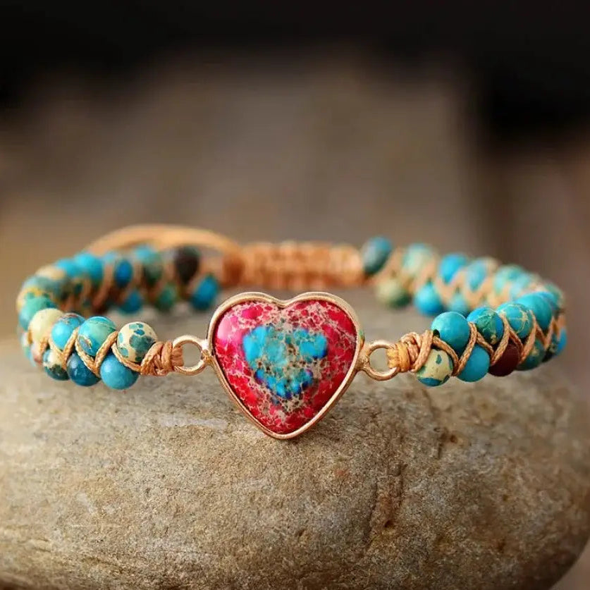 Beaded bracelet with a heart-shaped charm on a stone surface, featuring 'Free Spirit Shop' branding.