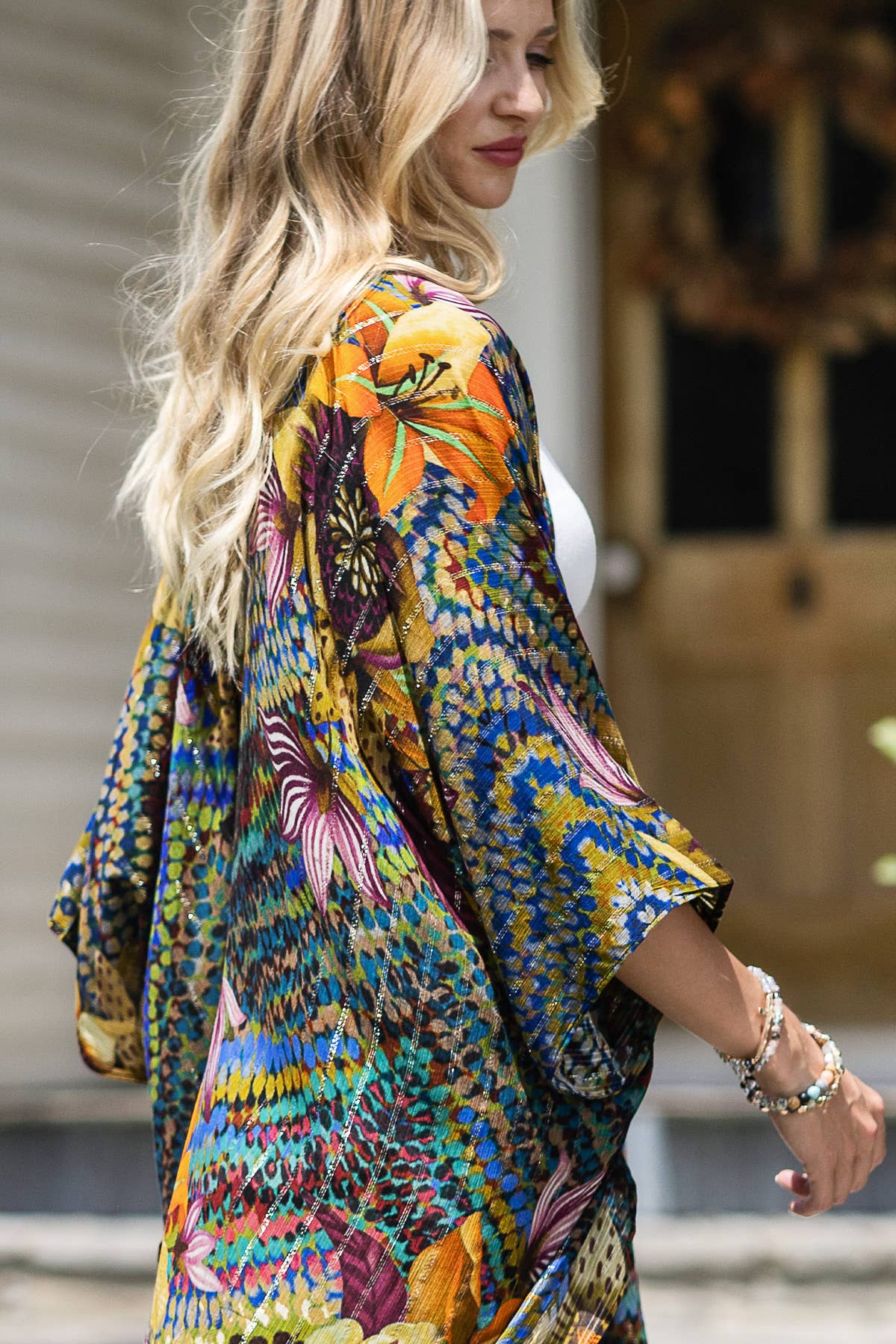 Woman wearing a colorful floral kimono-style garment with a blurred background