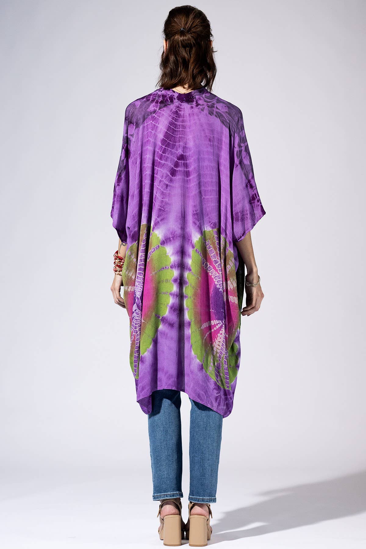 Person wearing a purple tie-dye dress with green patterns on a white background