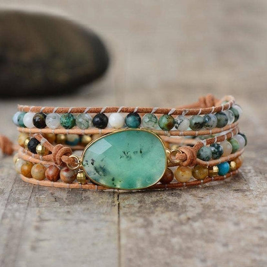Multistrand bracelet with a large green stone on a wooden surface, branded 'Free Spirit Shop'.