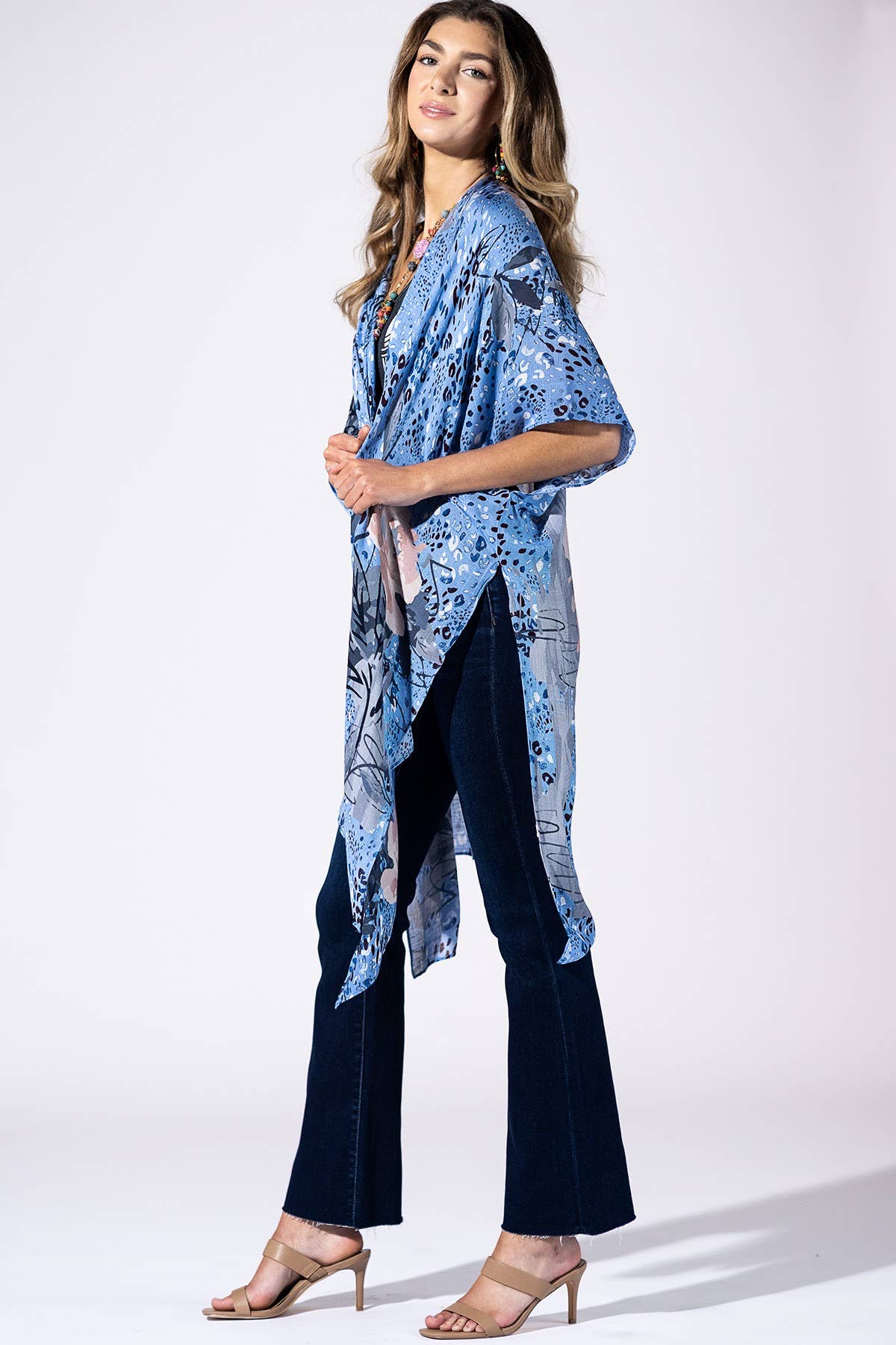 Woman wearing a blue floral kimono-style top and dark pants on a white background