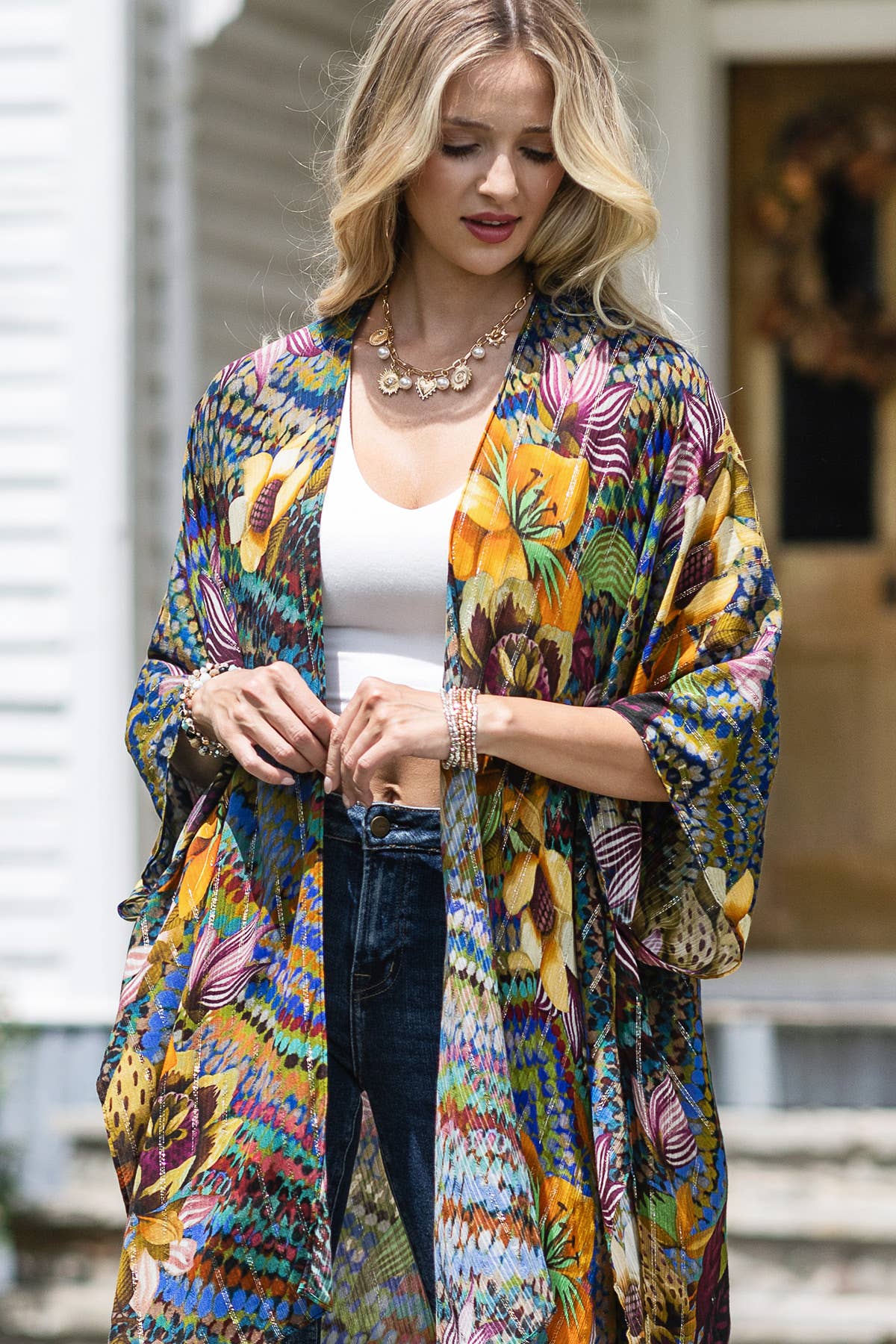 Woman wearing a colorful floral kimono over a white top and jeans.