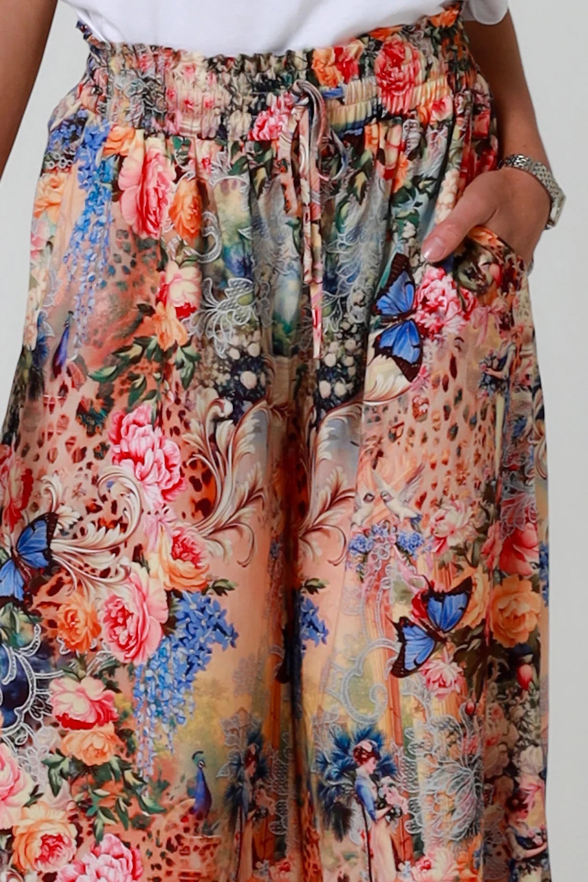 Colorful floral and butterfly patterned pants on a plain background
