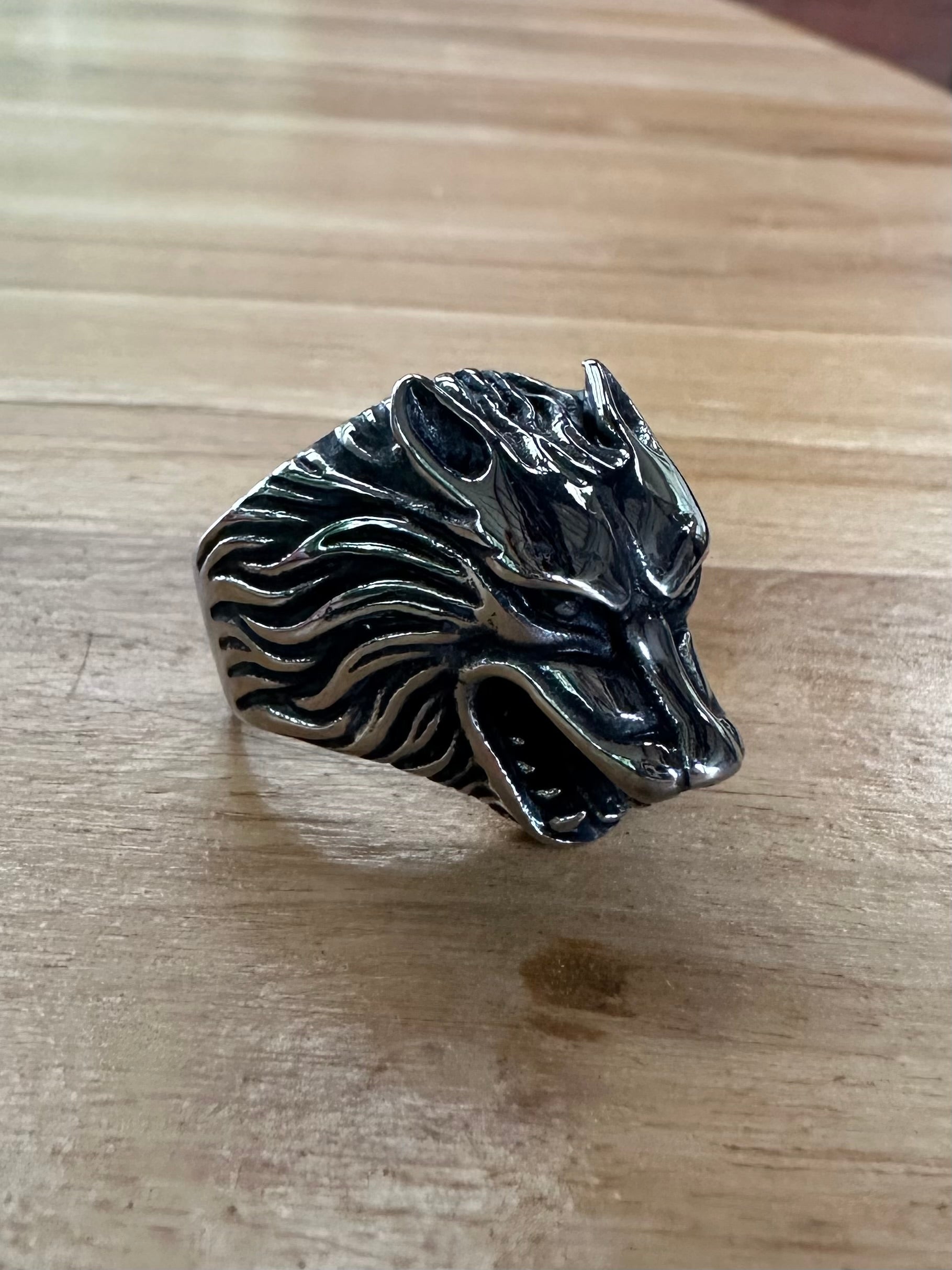 Silver wolf head ring on a wooden surface