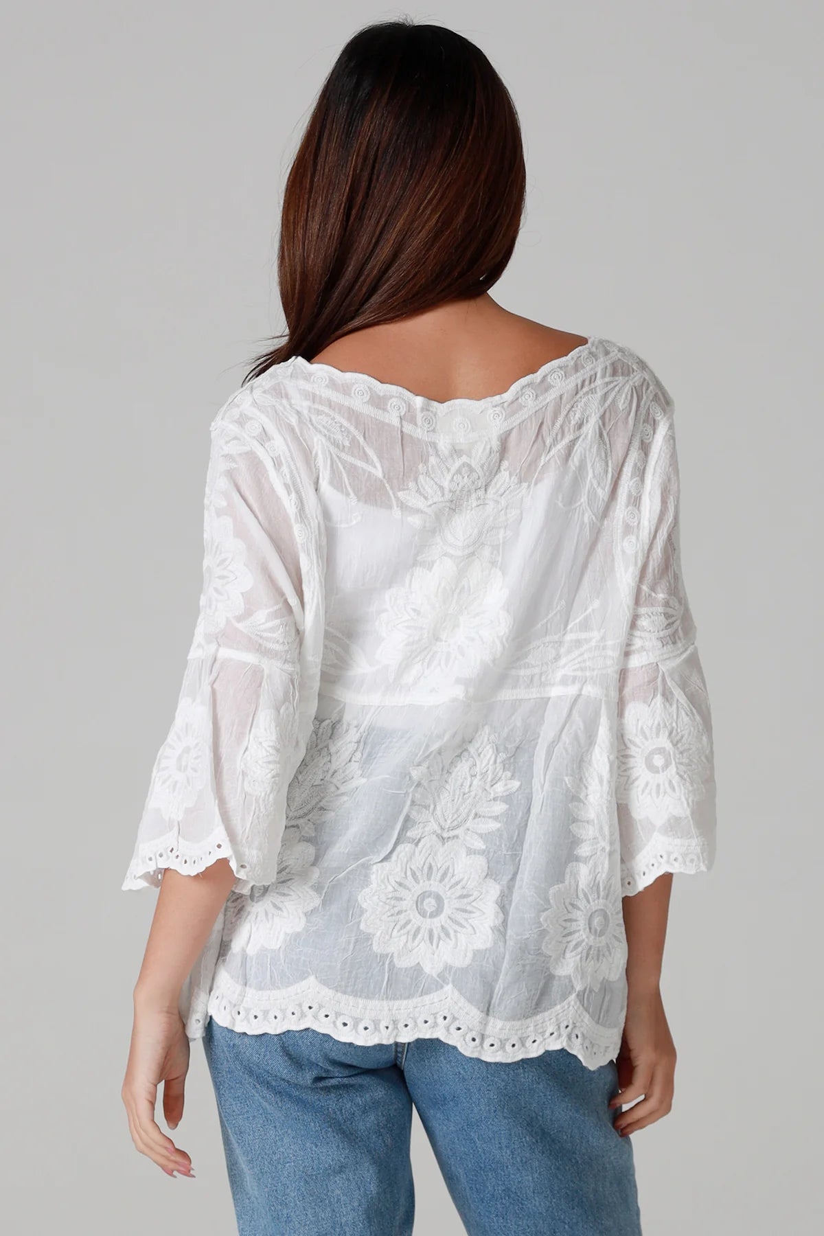 White lace top worn by a person on a gray background
