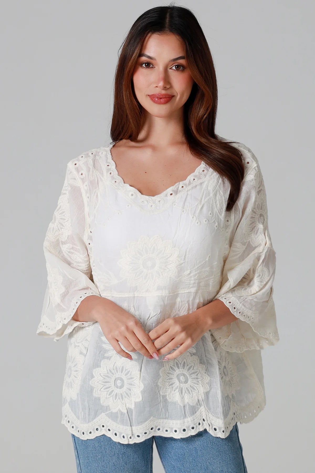 Woman wearing a white lace blouse against a gray background