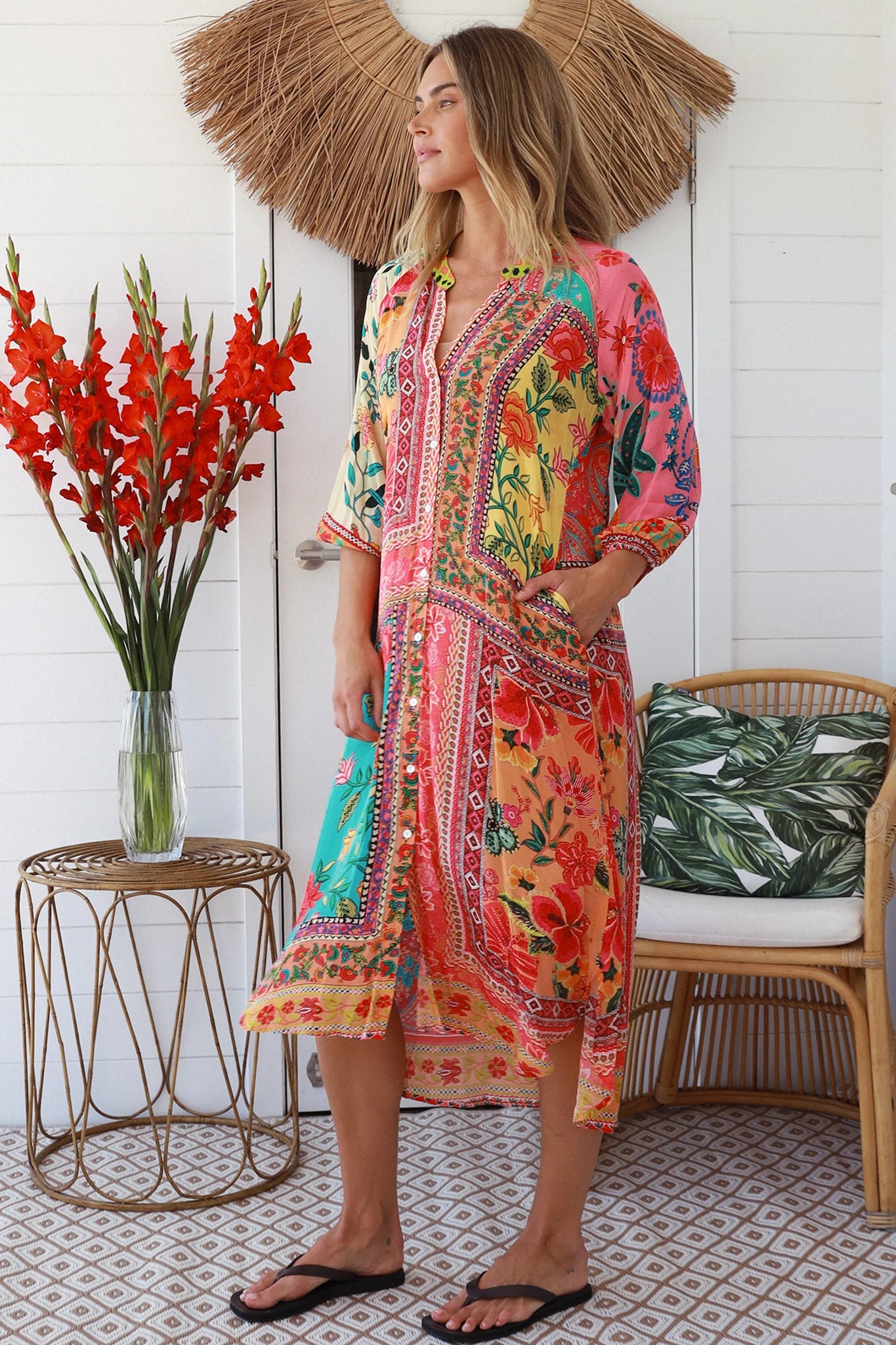 Woman wearing a colorful patterned dress standing in a room with decorative elements.
