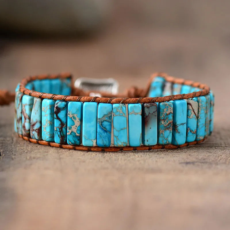 Turquoise stone bracelet with brown leather strap on a wooden surface