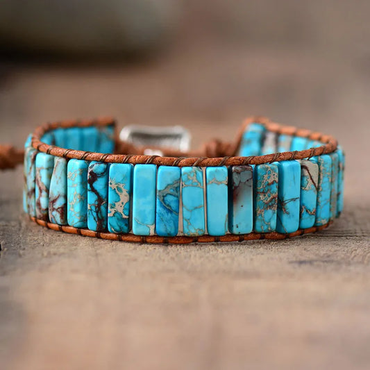 Turquoise stone bracelet with brown leather strap on a wooden surface