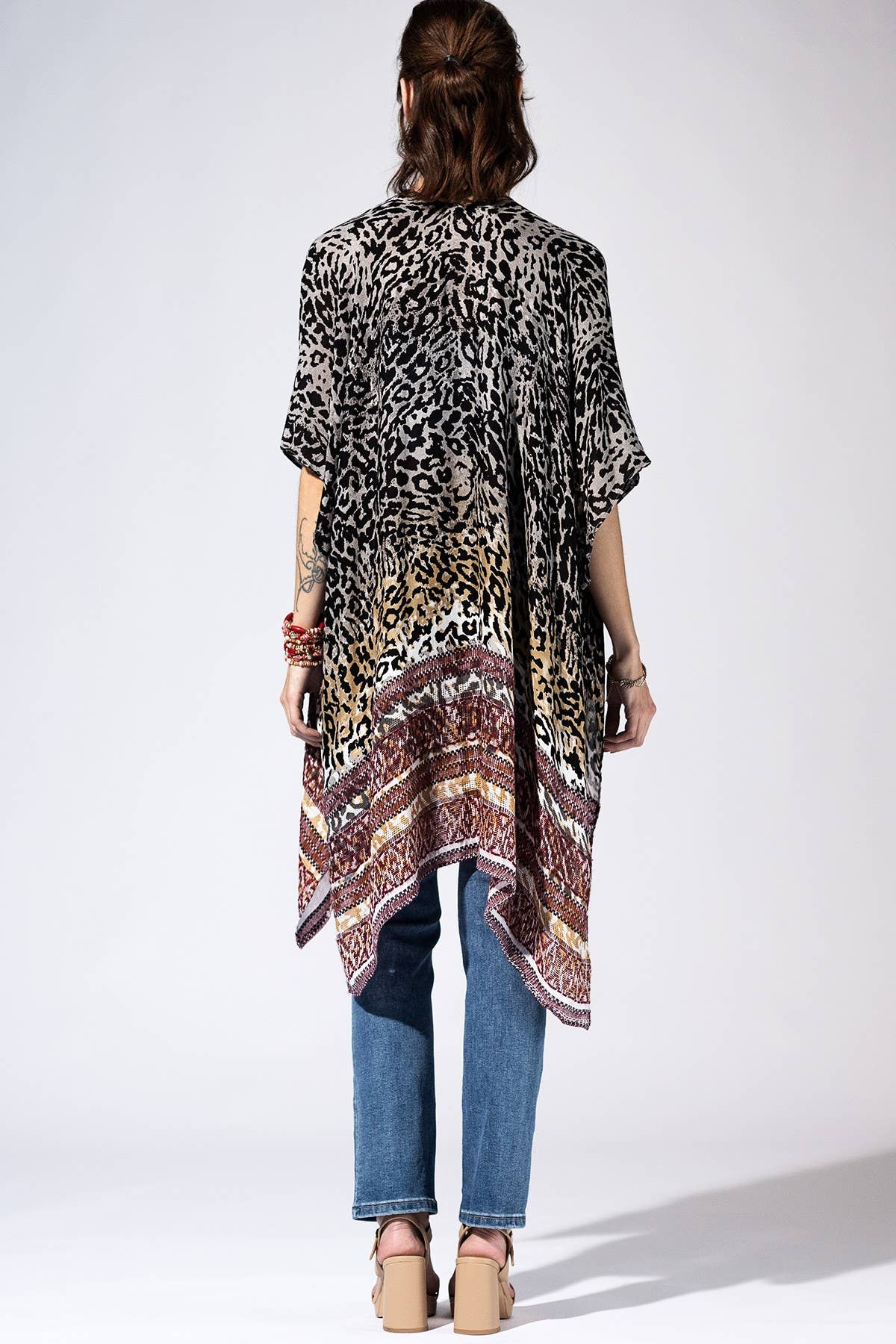 Person wearing a patterned kimono over a plain shirt with jeans on a white background