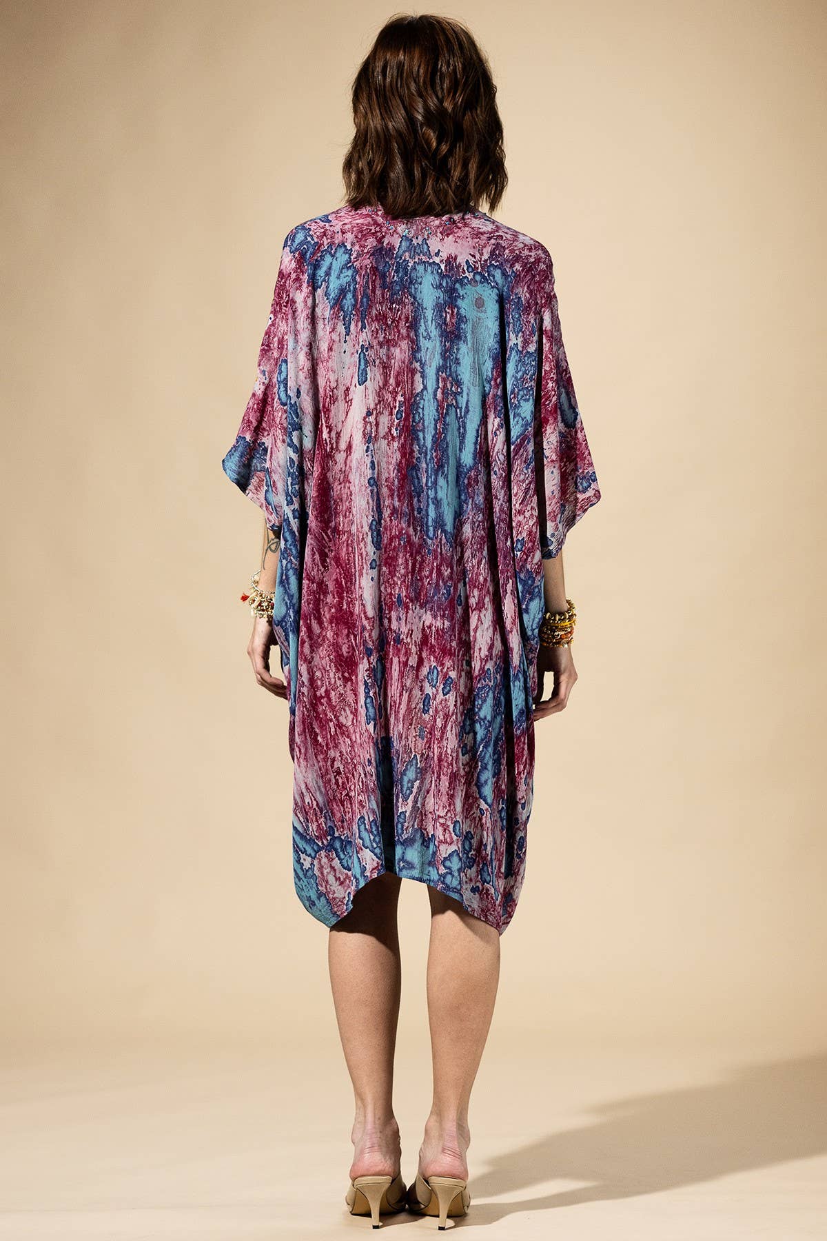Woman wearing a colorful kimono-style garment against a beige background