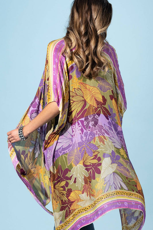 Woman wearing a colorful floral kimono-style garment against a light blue background