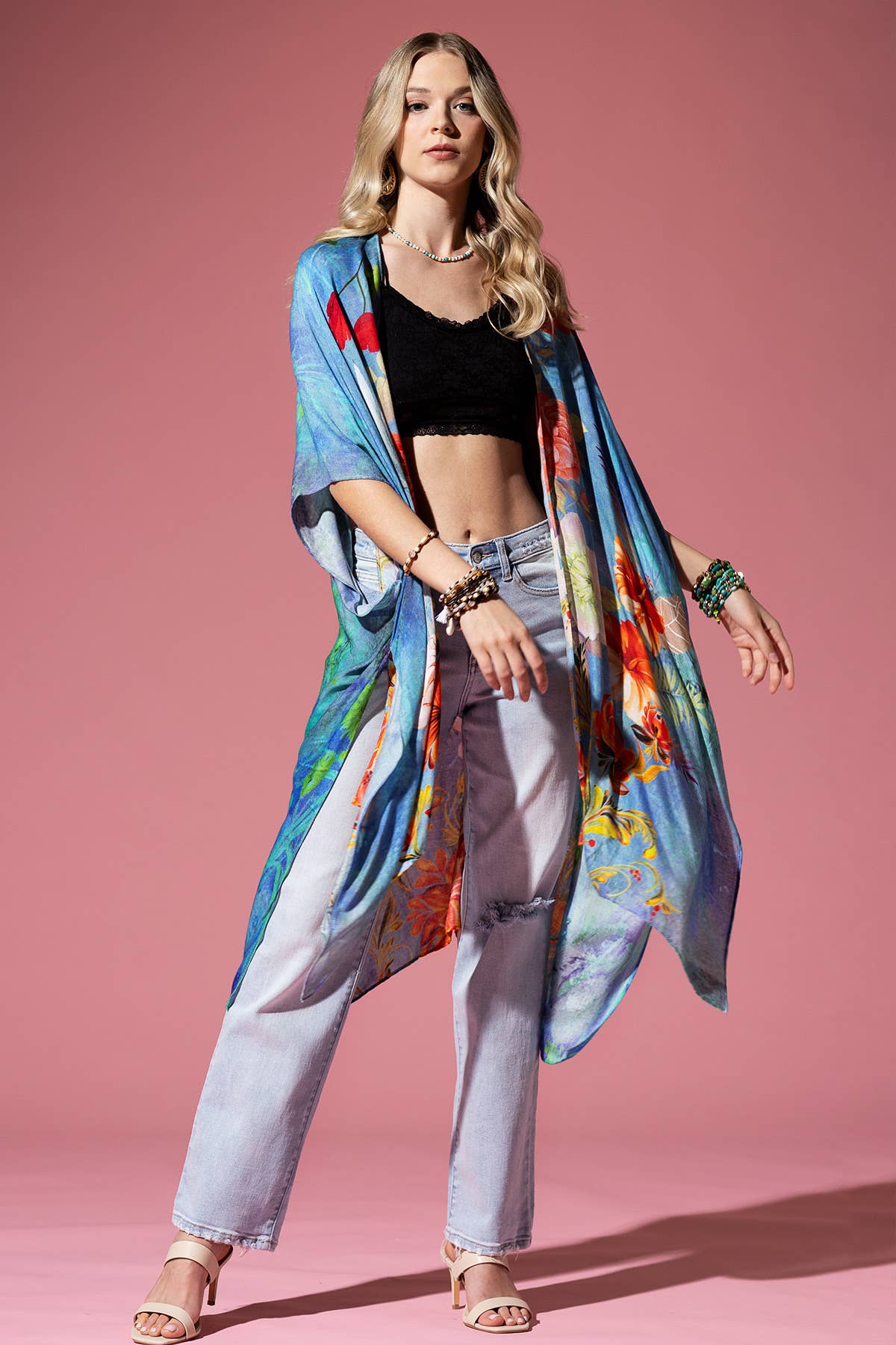 Woman wearing a colorful kimono-style garment against a pink background