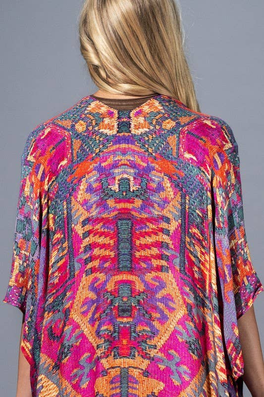 Colorful patterned top worn by a person on a gray background