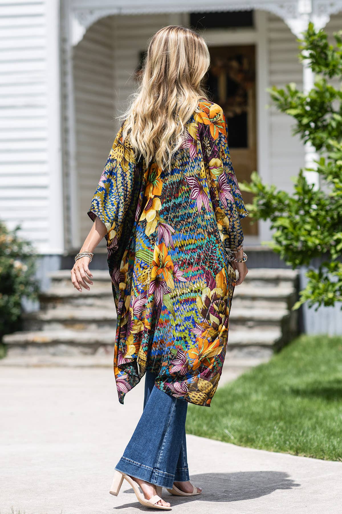 Woman wearing a colorful floral kimono in front of a house.