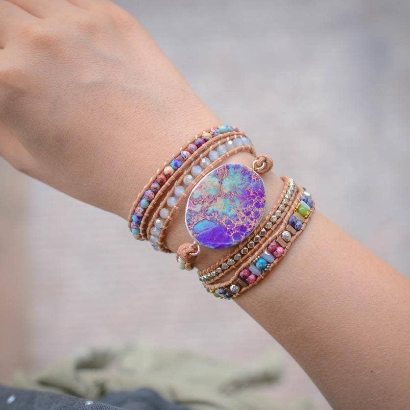 Multicolored beaded bracelet with a purple focal stone on a wrist, blurred background.