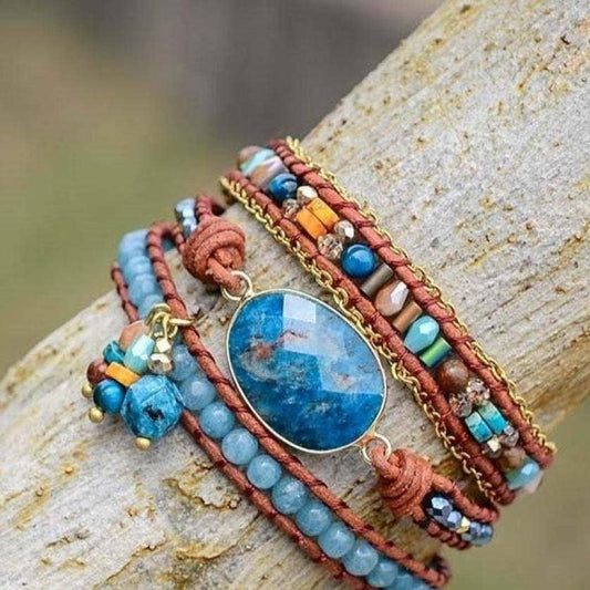Multistrand bracelet with blue stone and beads on a wooden surface.