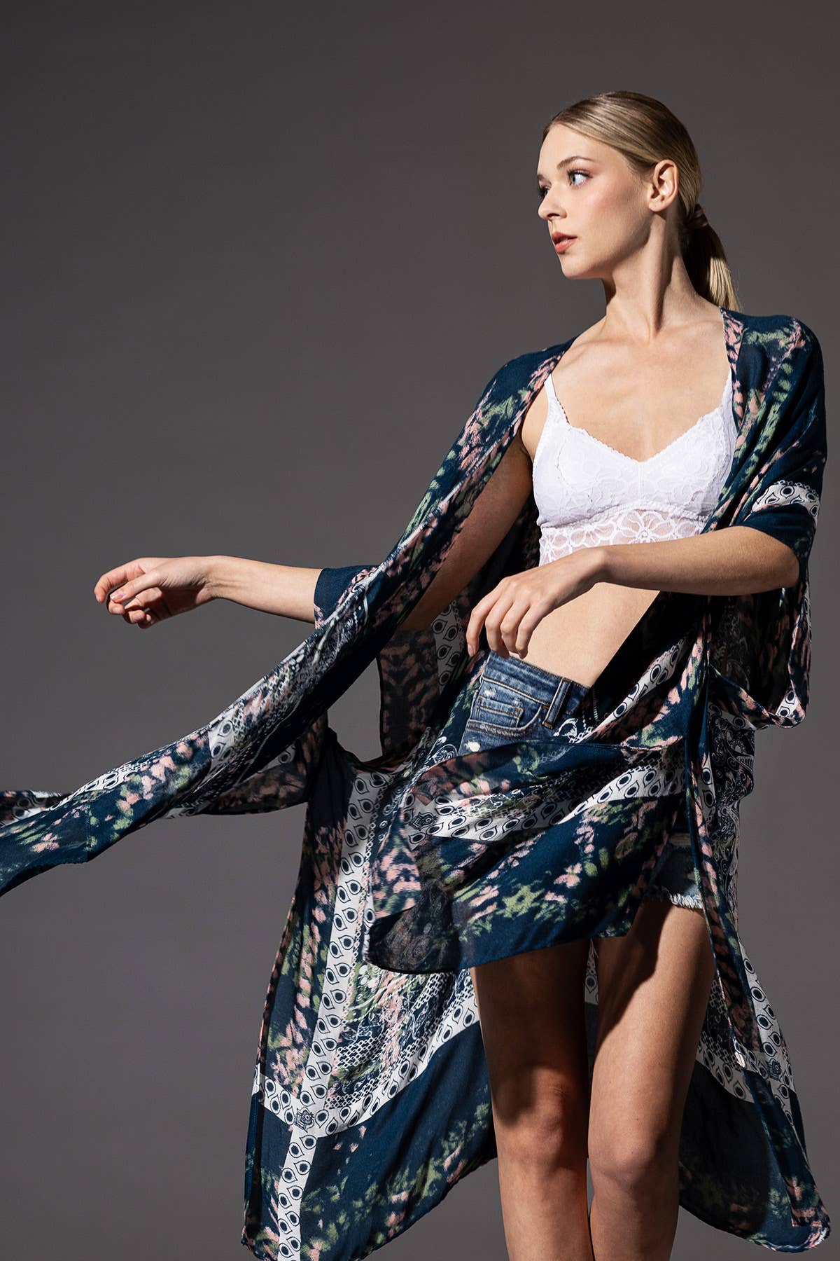 Woman wearing a floral kimono over a white top against a gray background