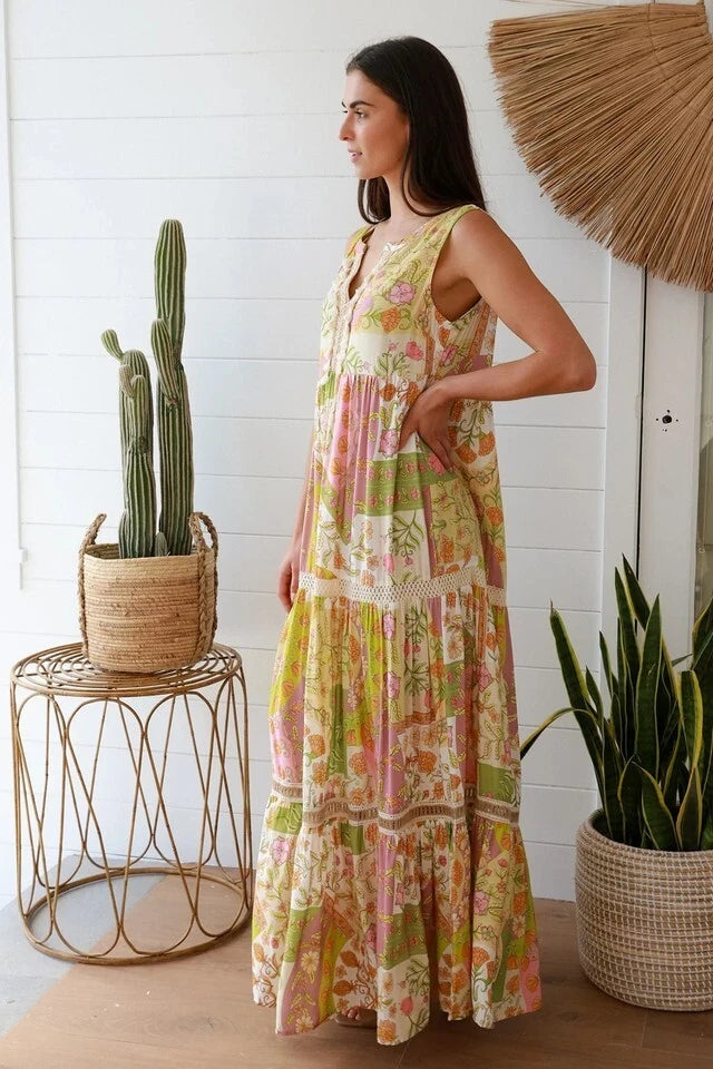 Woman in a colorful dress standing in a room with plants and a decorative umbrella.