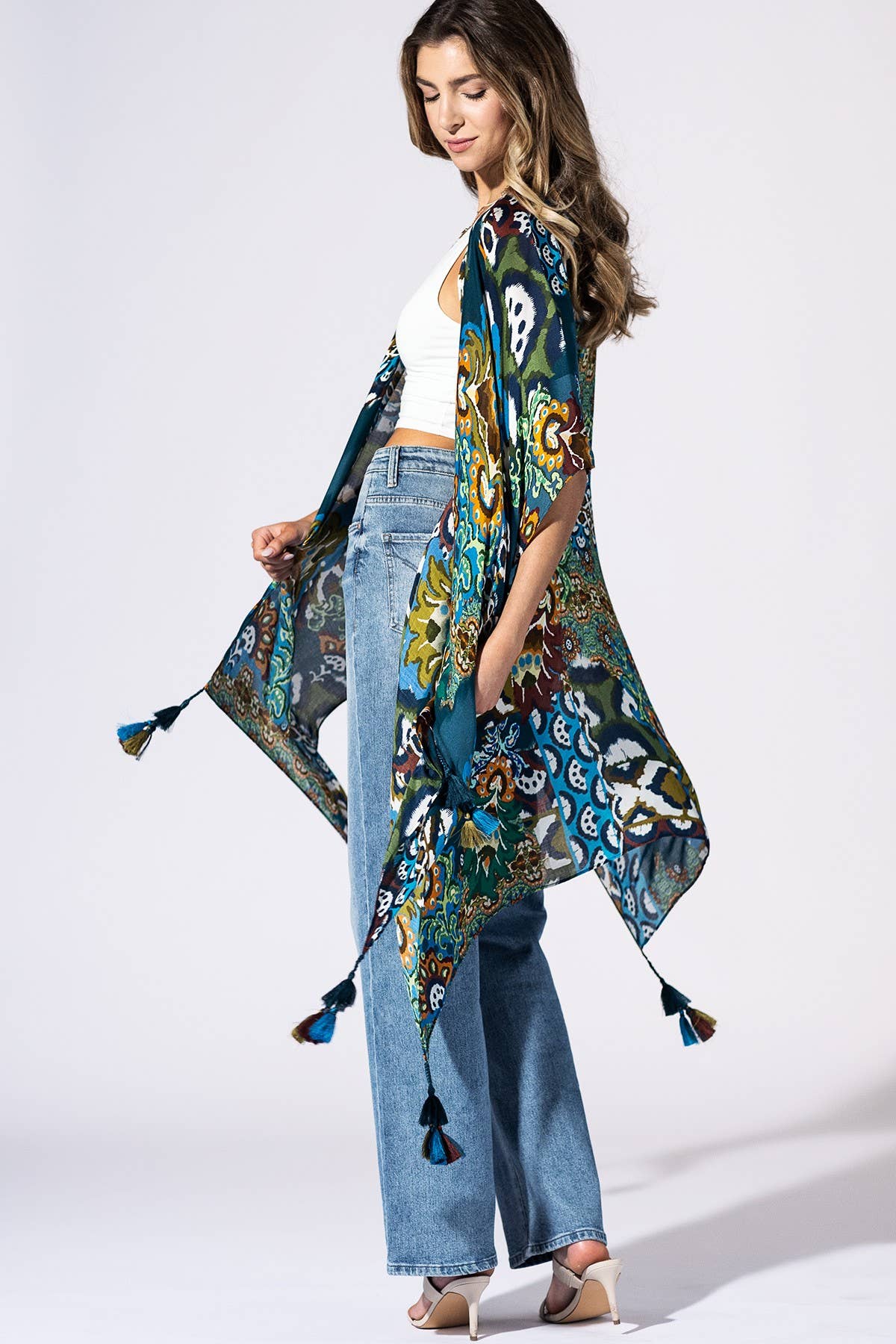 Woman wearing a colorful patterned scarf with tassels on a white background