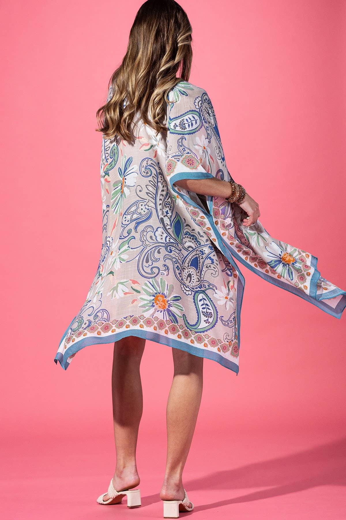 Woman wearing a colorful patterned kimono against a pink background