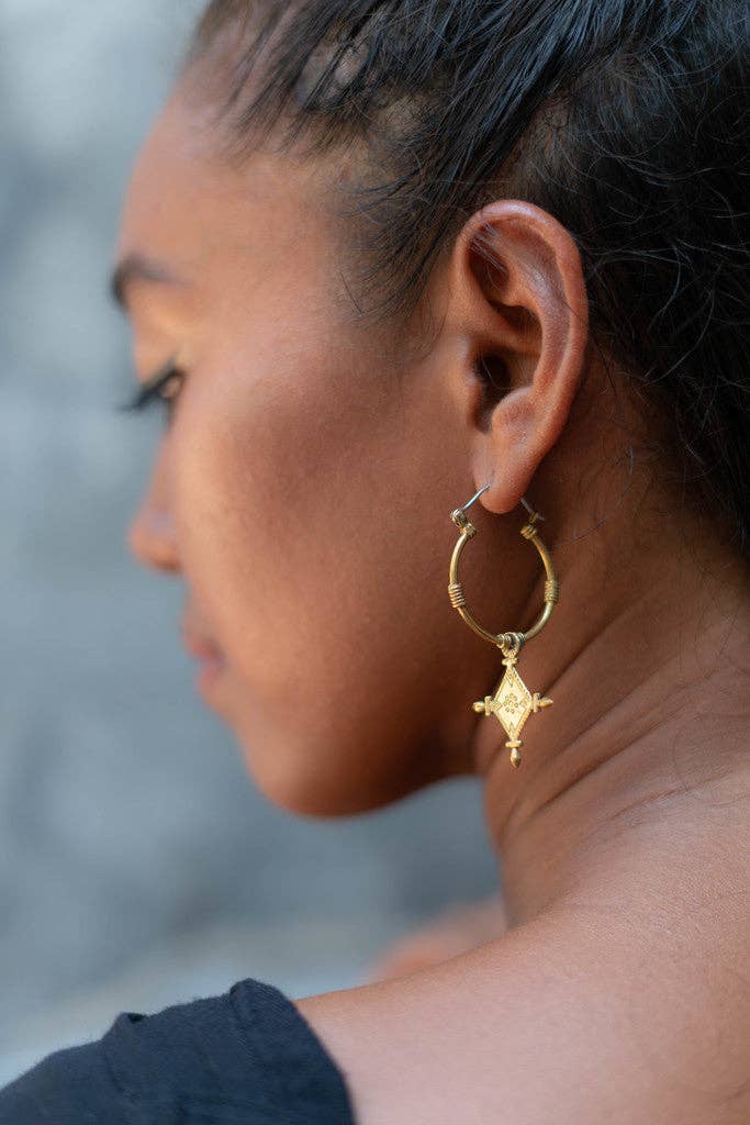 Close-up of a person wearing a gold hoop earring with a star design.
