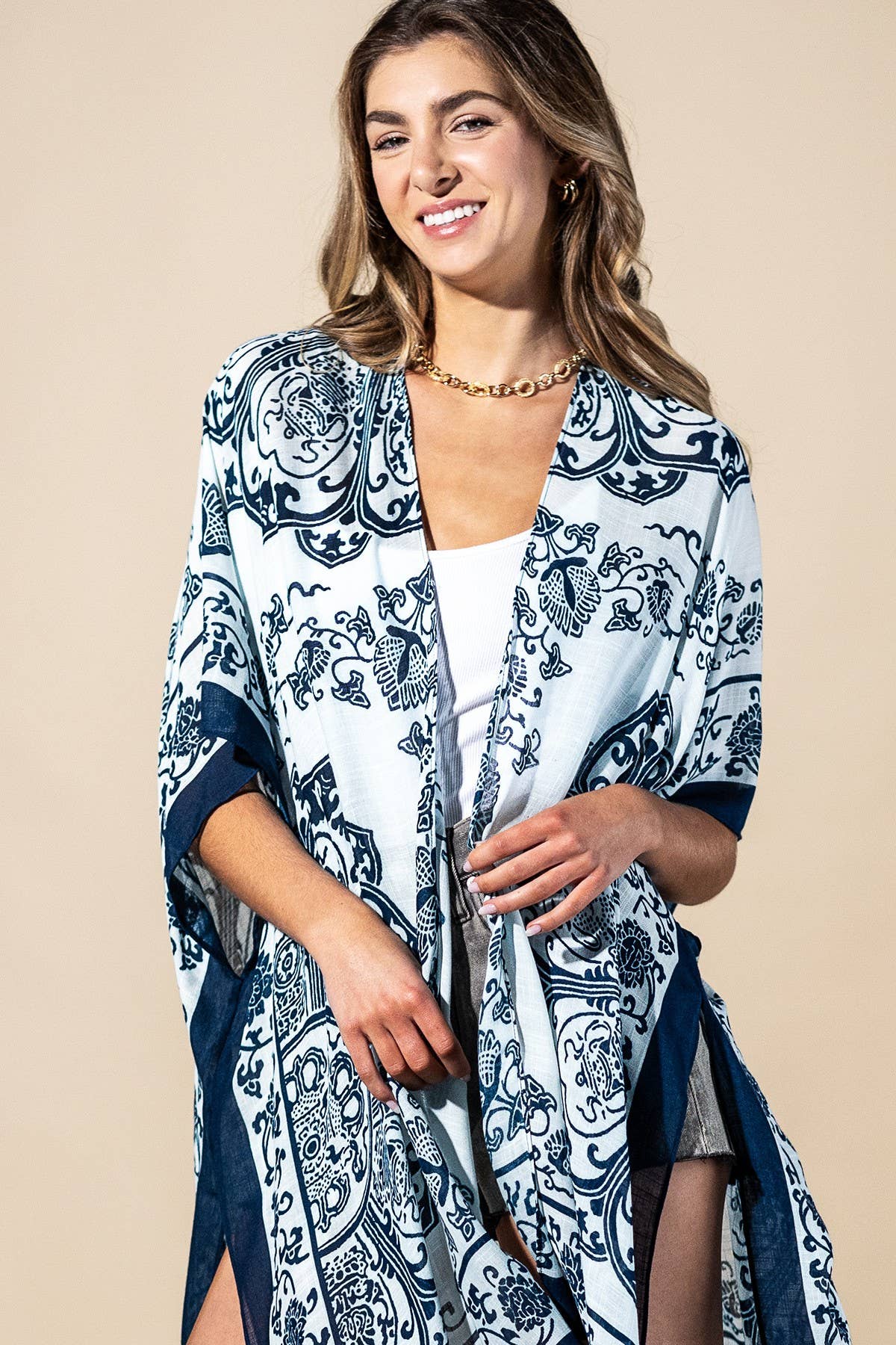 Woman wearing a blue and white patterned kimono over a white top on a beige background