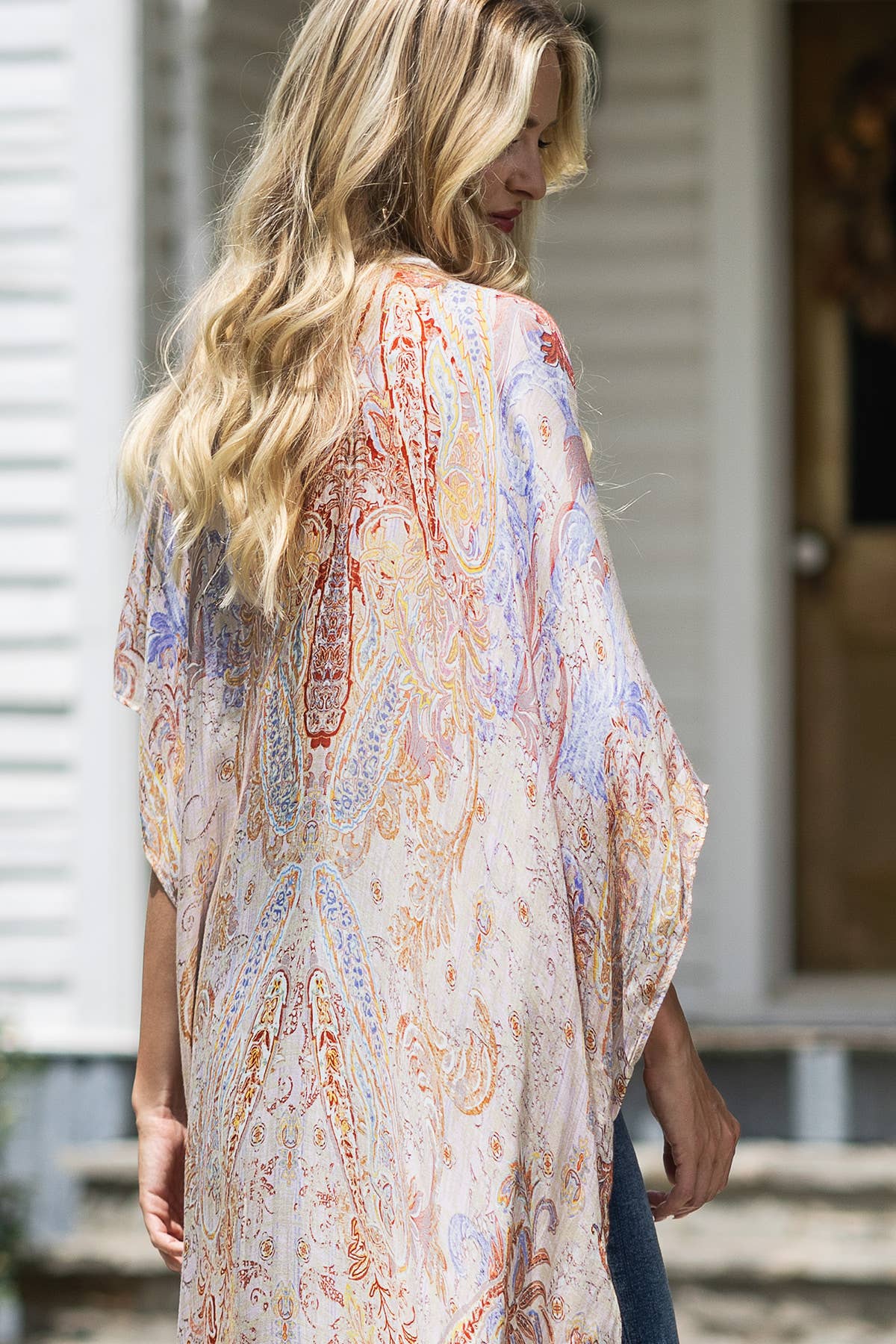 Woman wearing a patterned kimono-style garment outdoors.