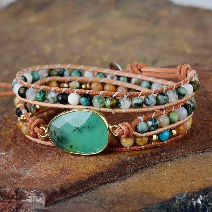 Multistrand bracelet with a green stone on a stone surface, branded 'Free Spirit Shop'.