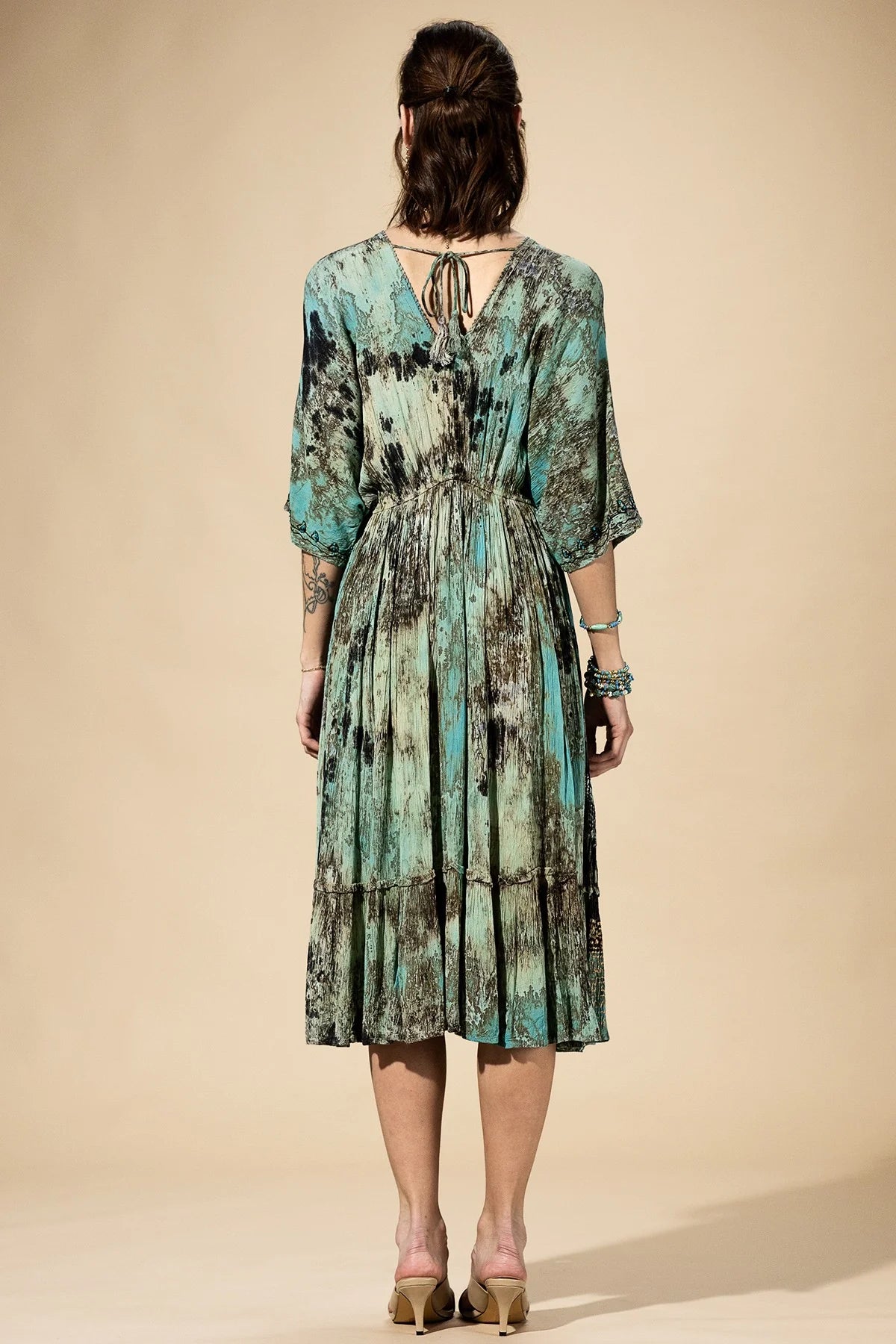 Woman wearing a patterned dress against a beige background