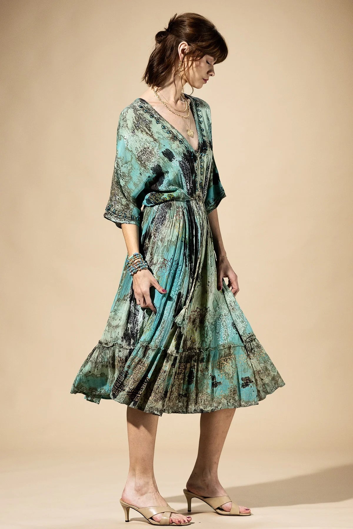 Woman wearing a green and blue patterned dress on a beige background