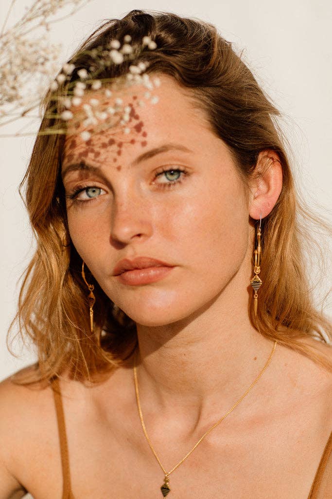 Woman with gold jewelry against a neutral background