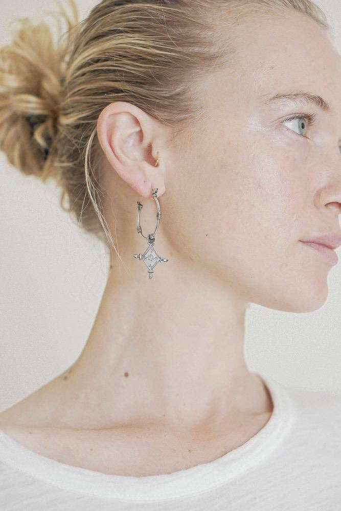 Close-up of a person wearing a star-shaped earring on a plain background