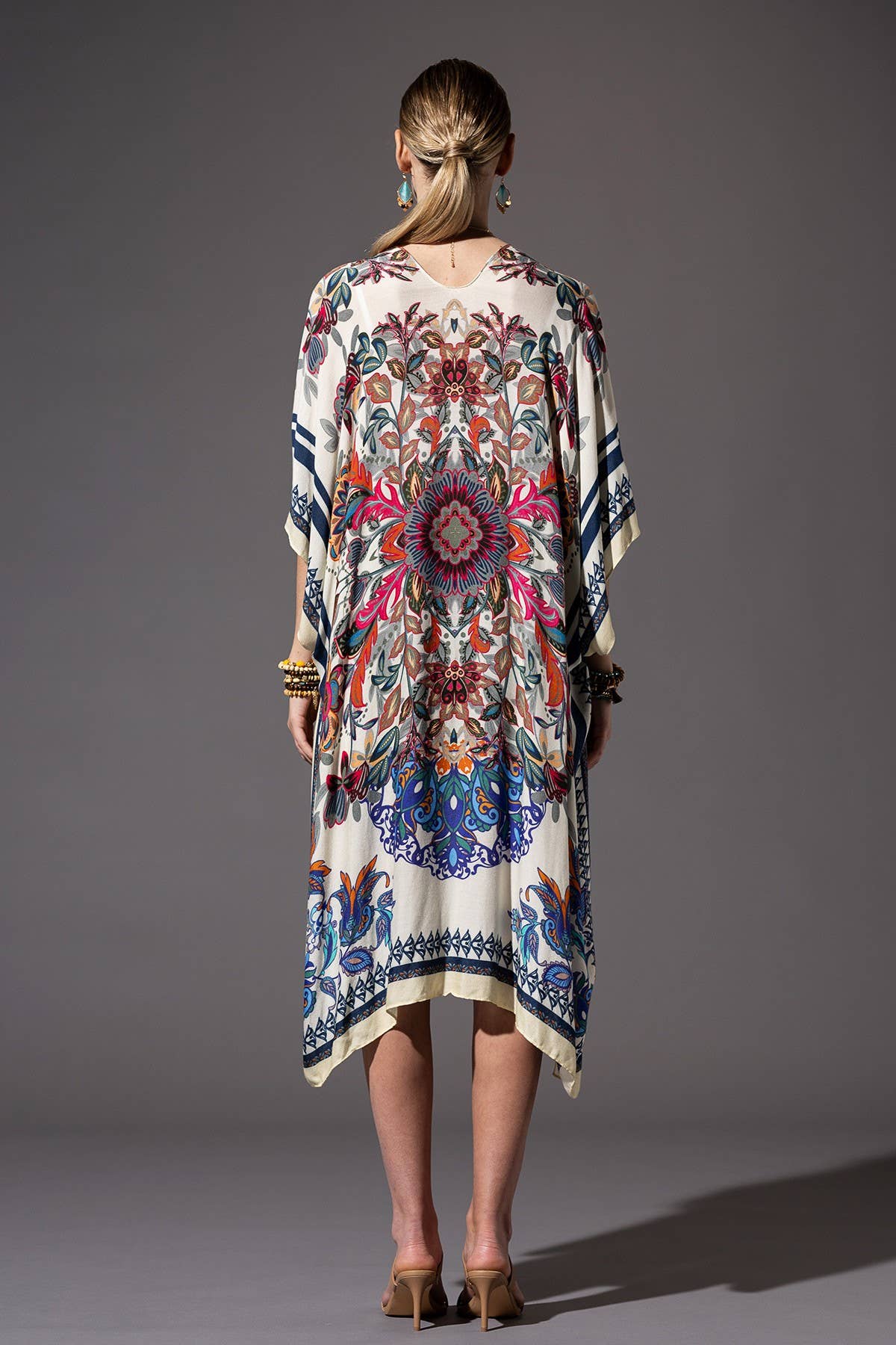 Woman wearing a colorful patterned dress against a gray background