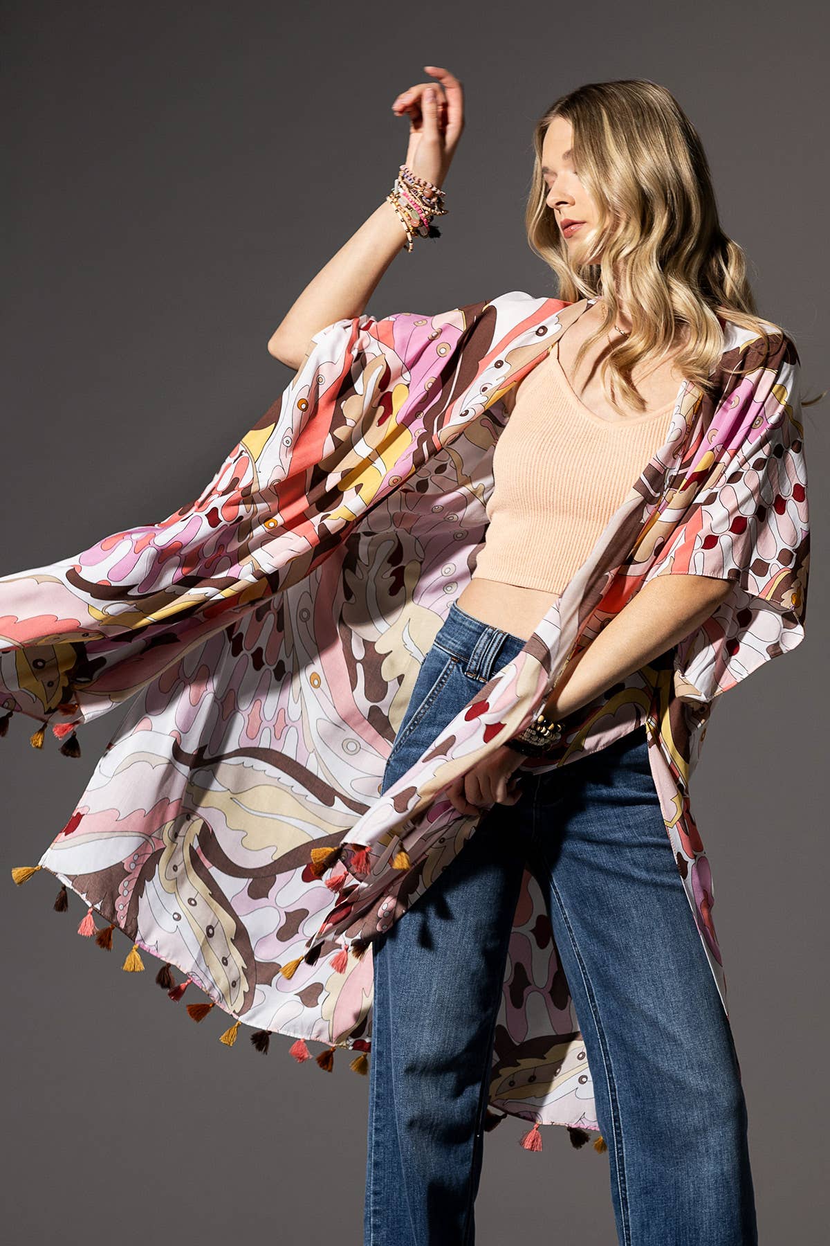 Woman wearing a colorful patterned kimono with tassels against a gray background