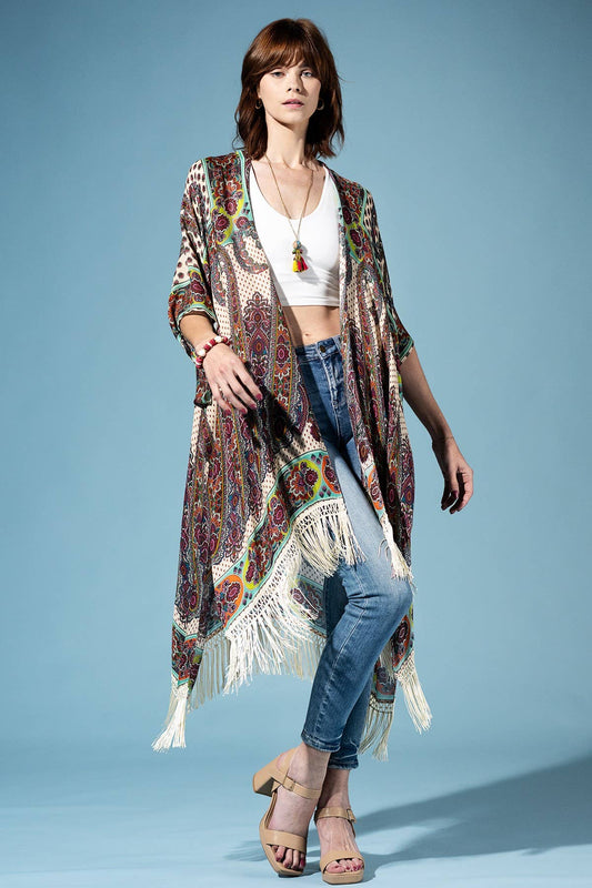 Woman wearing a patterned kimono over a white top and blue jeans on a light blue background