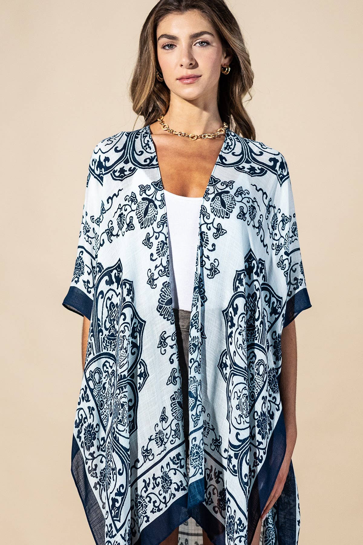 Woman wearing a blue and white patterned kimono over a white top on a beige background