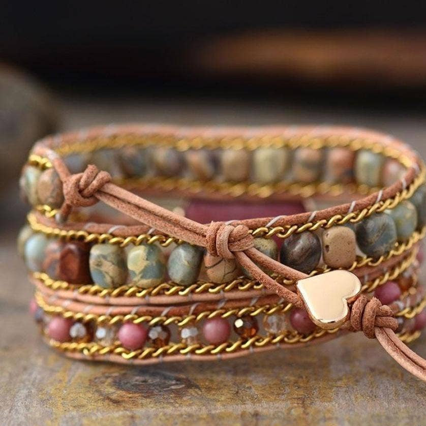 Multistrand beaded bracelet with leather wrap and heart charm on a rustic surface, 'Free Spirit Shop' branding visible.