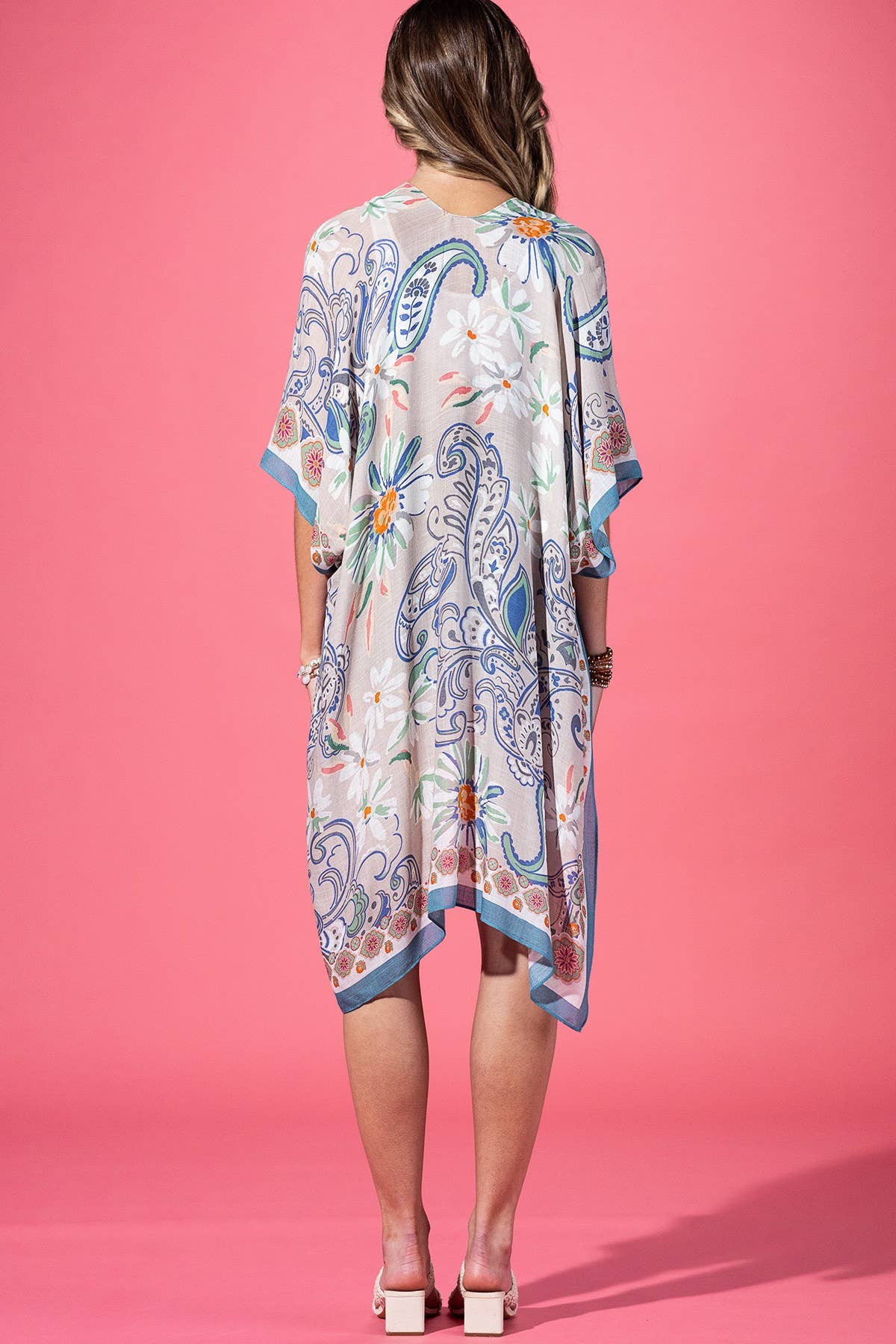 Woman wearing a patterned dress against a pink background