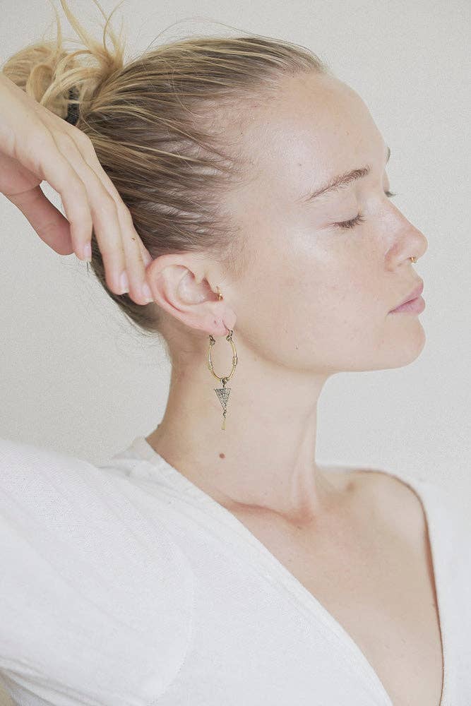 Close-up of a person wearing hoop earrings with a plain background