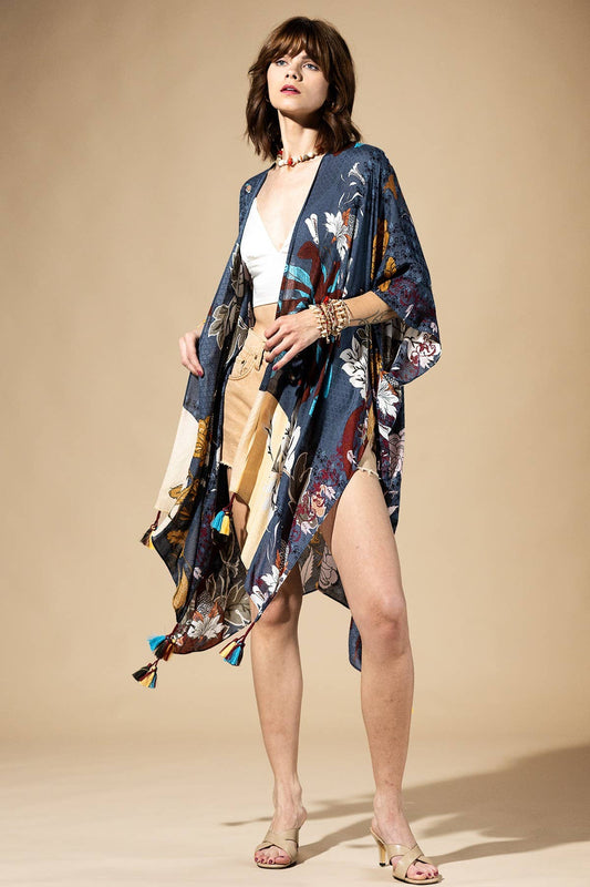 Woman wearing a floral kimono over a white top and beige shorts on a beige background