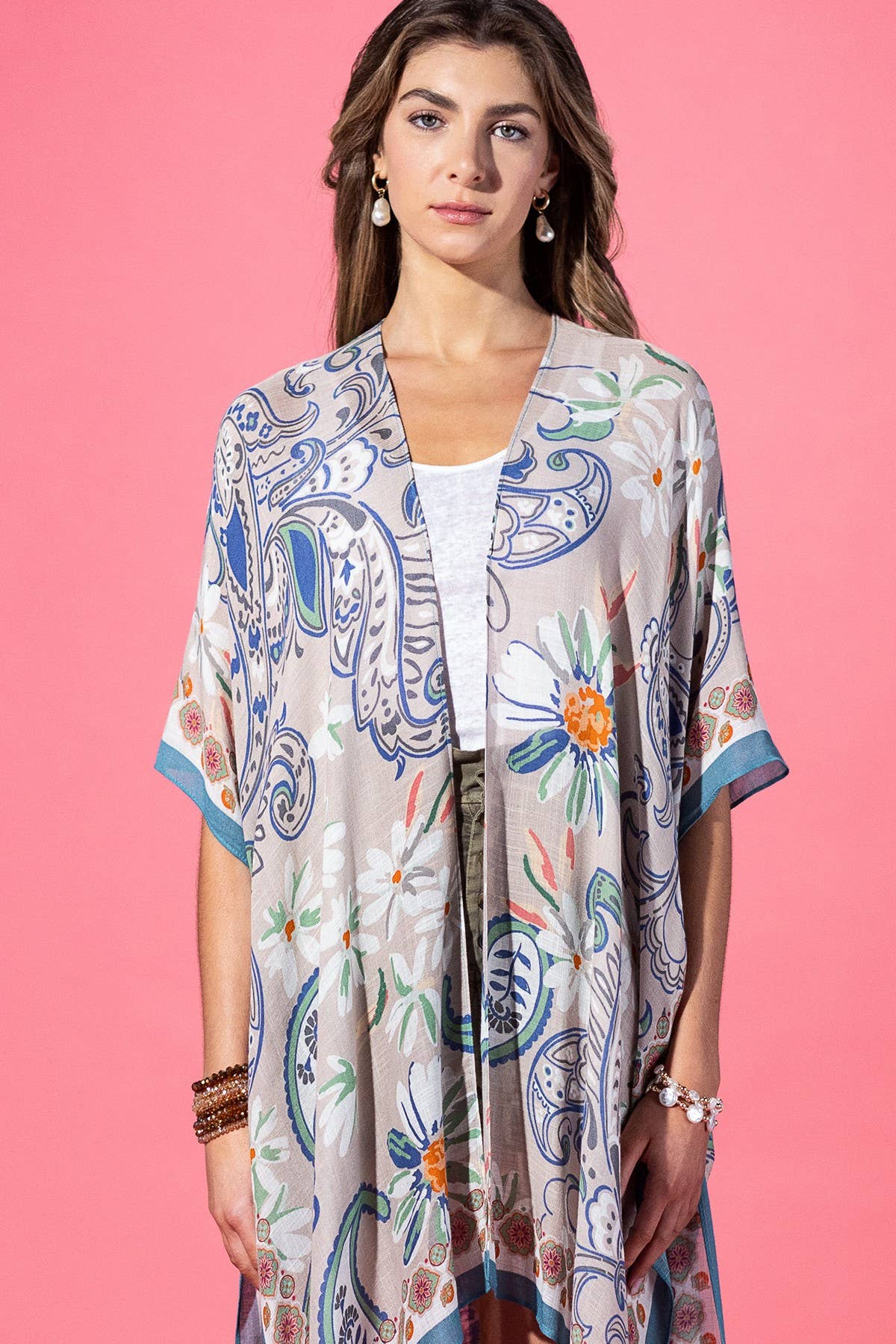 Woman wearing a floral kimono-style garment against a pink background