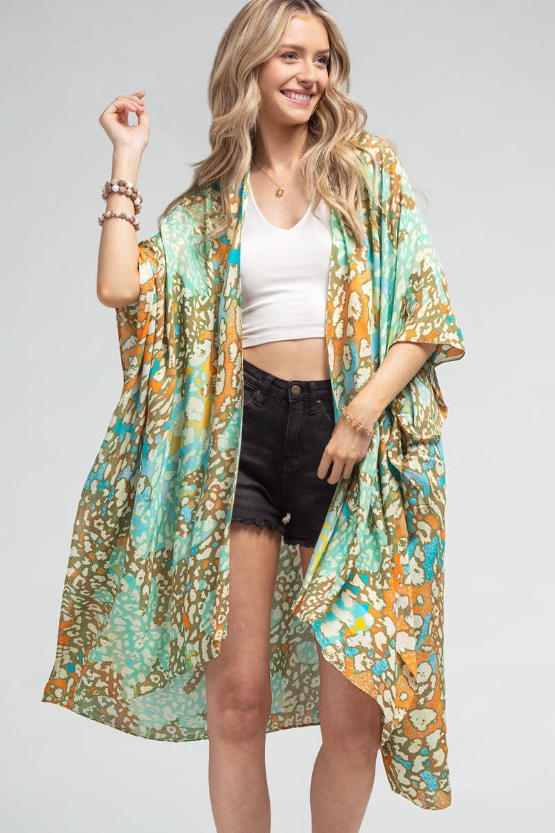 Woman wearing a colorful kimono over a white top and black shorts on a gray background