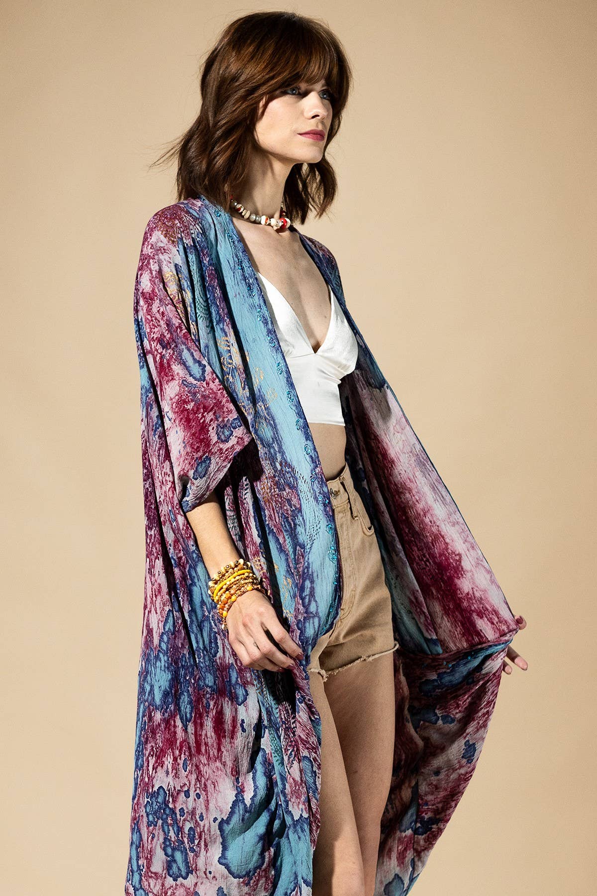 Woman wearing a colorful kimono-style garment on a beige background