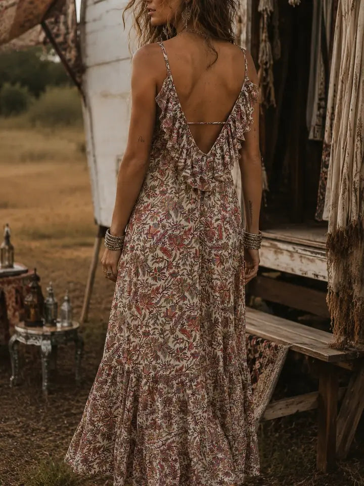 Woman in a floral dress standing in front of a rustic wooden structure with a field background.