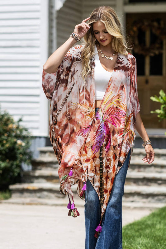 Woman wearing a colorful floral kimono with tassels in front of a house.