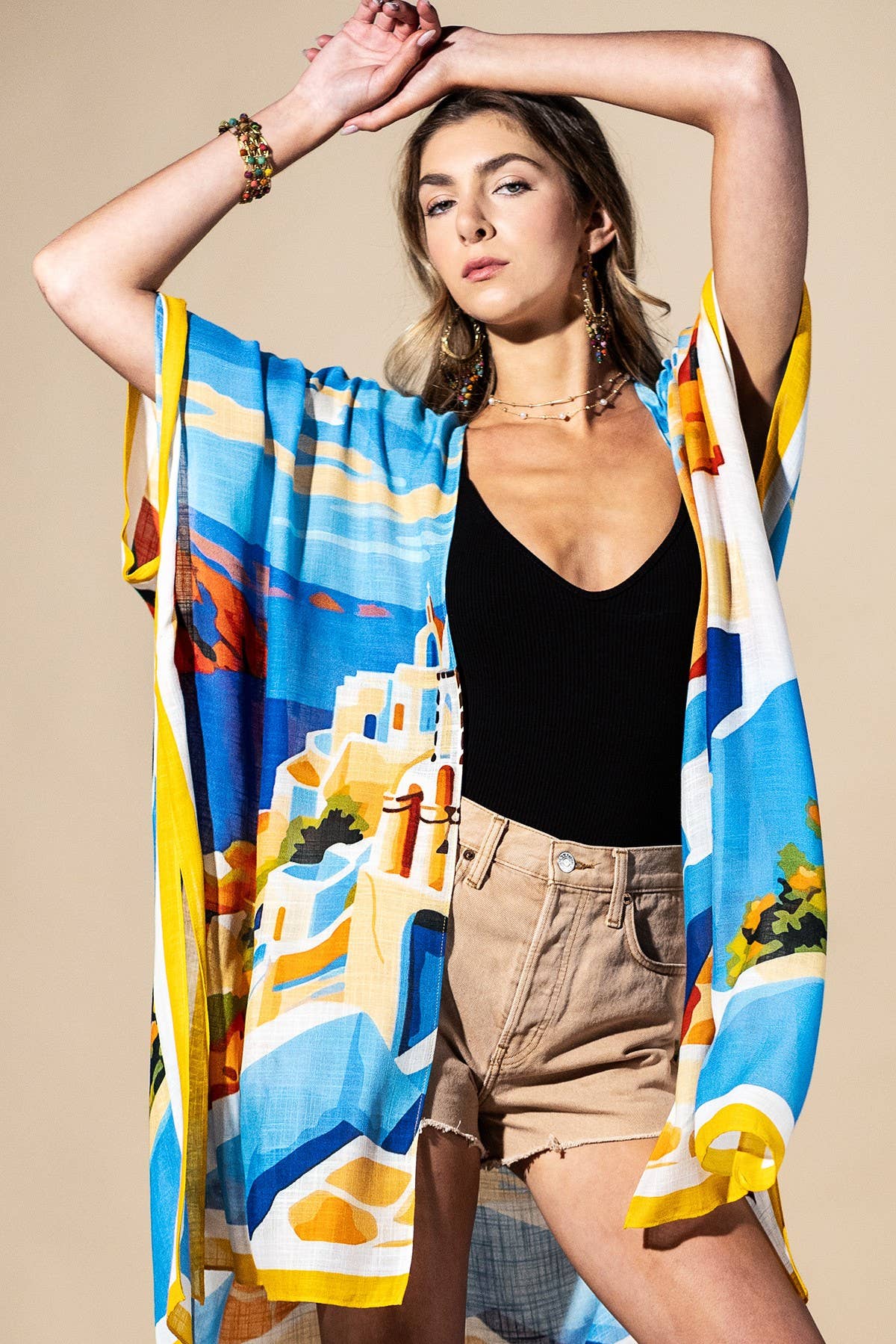 Woman holding a colorful beach towel with a scenic design on a beige background