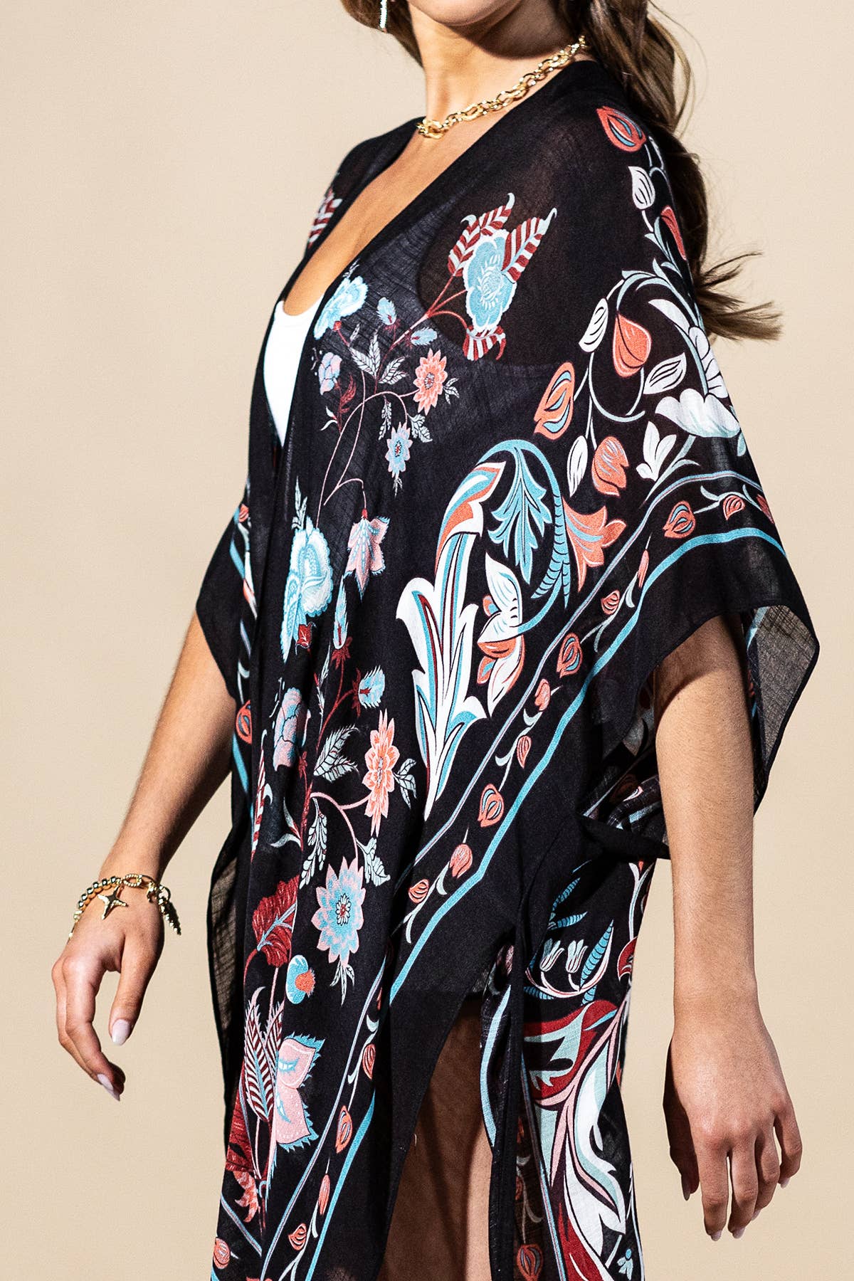Woman wearing a black floral kimono-style garment against a beige background