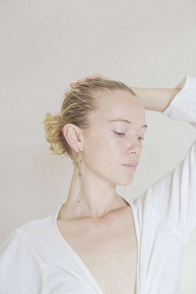 Woman with a bun wearing a white top against a plain background