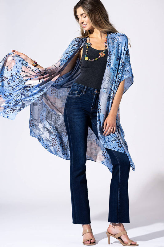 Woman wearing a blue floral kimono over a black top and jeans on a white background